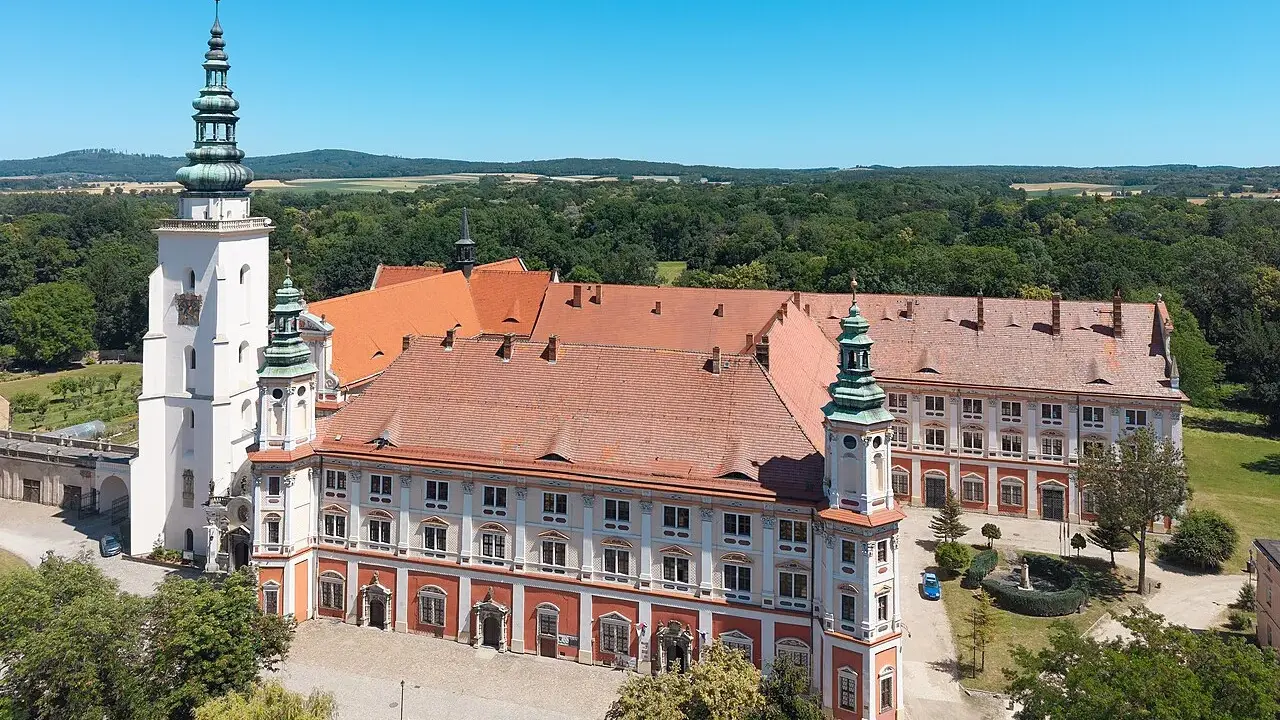 Imponujący Henryków zamek z wieżami i czerwonymi dachami, otoczony zielenią.