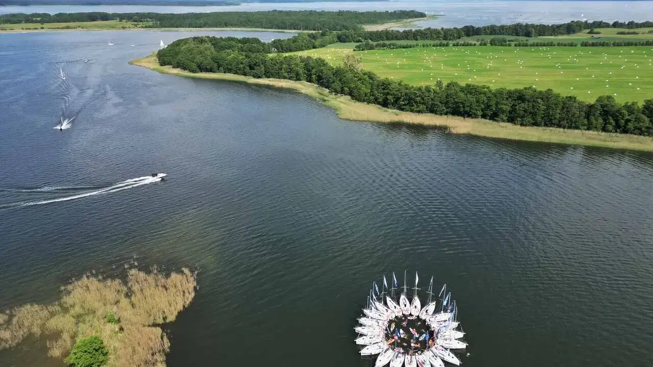 Kwiat z żaglówek na jeziorze, otoczony zielonymi polami i lasami. Piękny widok na Warmia i Mazury.