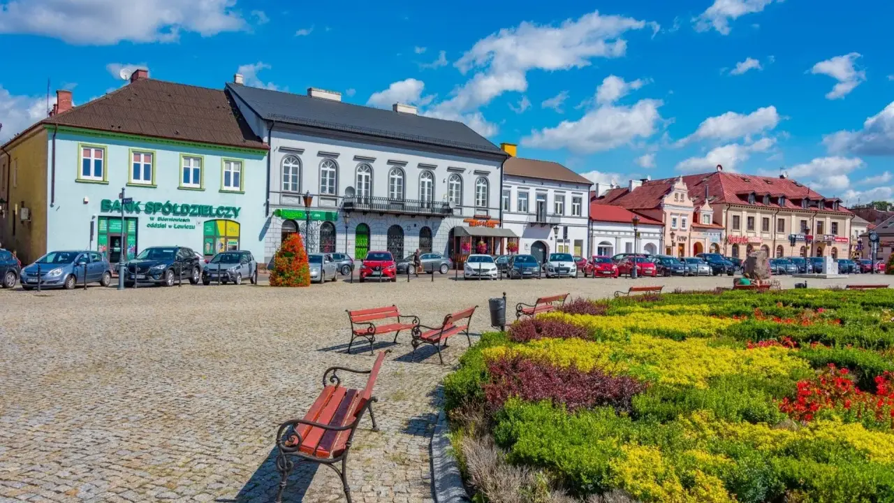 Kolorowy rynek z kwitnącymi rabatami i ławkami, idealne miejsce na wyjazd na weekend.