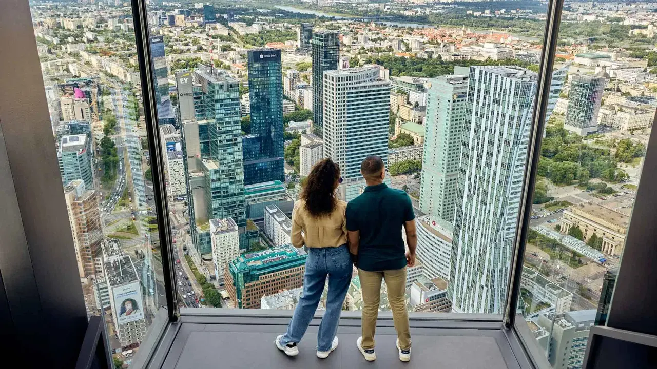Para zwiedzająca Varso Tower taras widokowy, podziwia panoramę Warszawy.