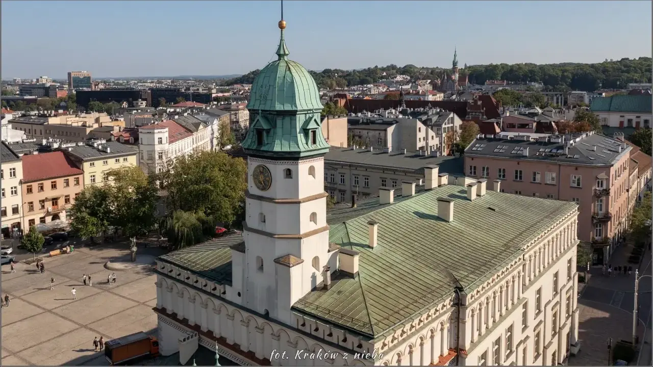 Widok na rynek na Kazimierzu w Krakowie z wieżą ratuszową i zielonymi dachami.