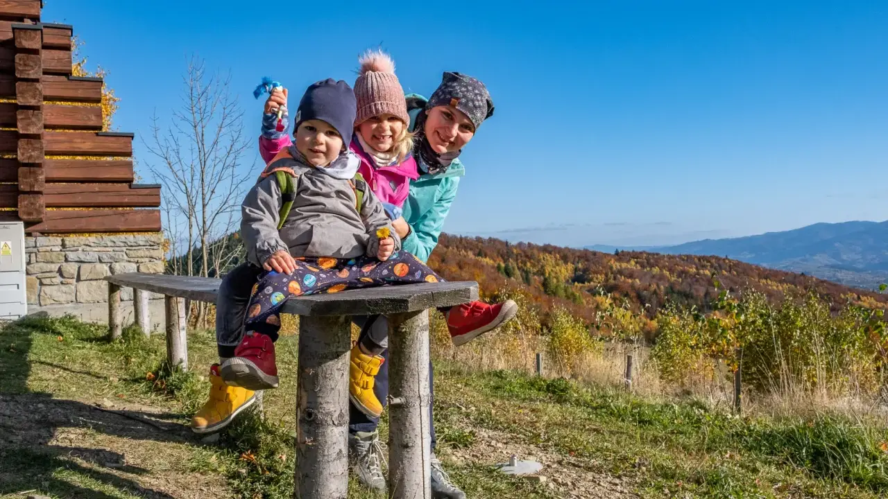 Rodzina na ławce z widokiem na jesienne góry. Góra Modyń w tle.