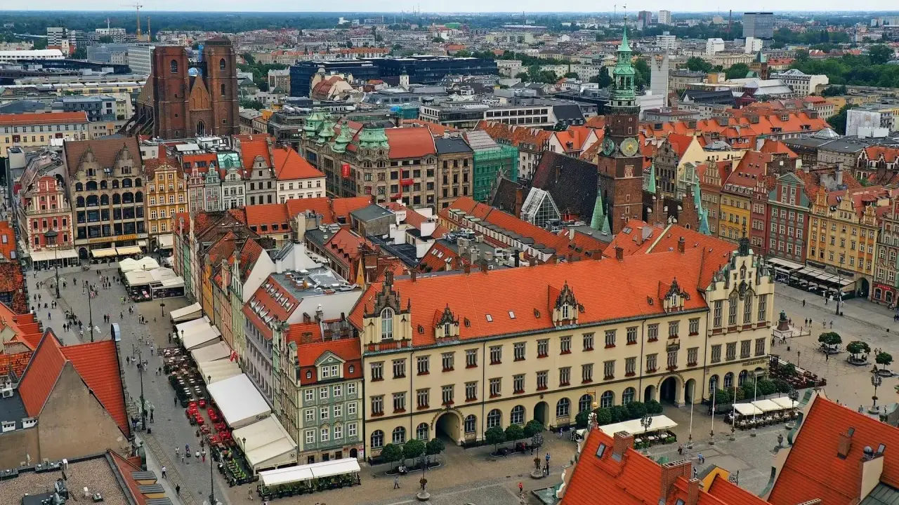 Widok z góry na kolorowy rynek z kamienicami, ratuszem i kościołem. To chyba najładniejszy rynek w Polsce, tętniący życiem.