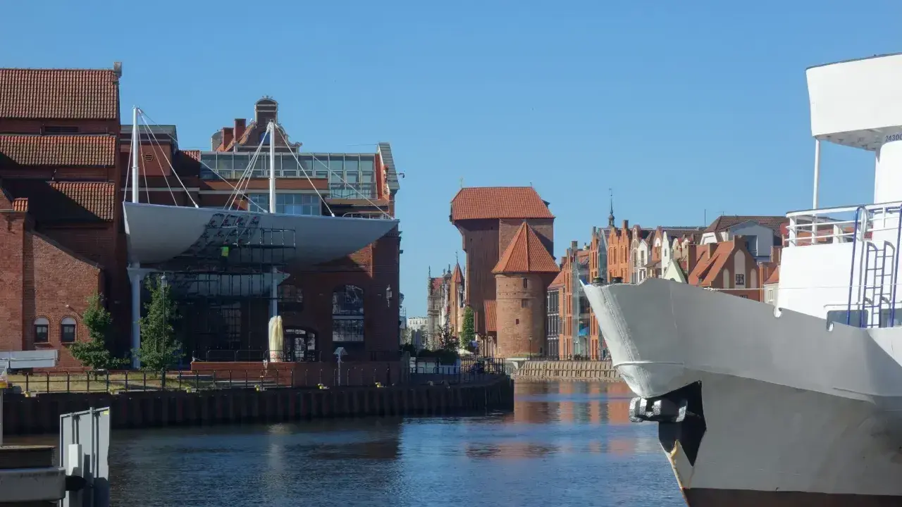 Gdańsk Starówka atrakcje: biały statek na pierwszym planie, w tle zabytkowe kamienice i Żuraw.