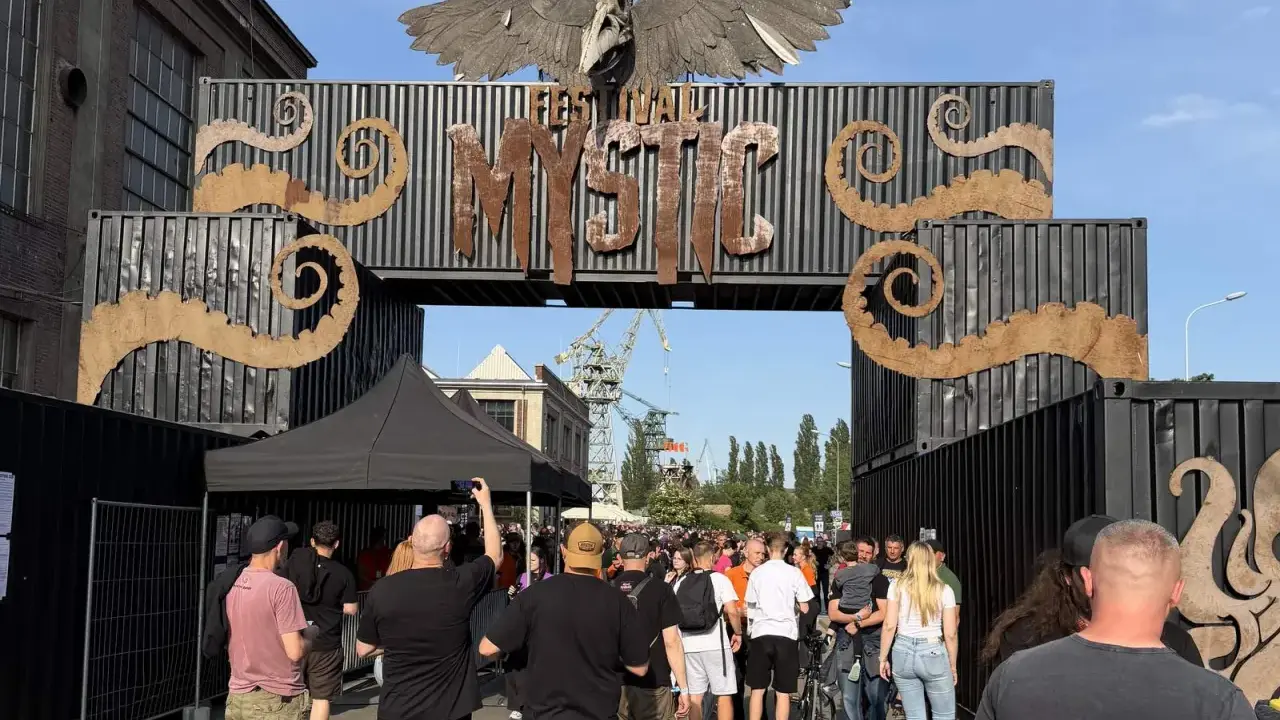 Tłum ludzi wchodzi przez bramę festiwalową "Mystic". To jedno z wielu wydarzeń kulturalnych, takich jak festiwale filmowe w Polsce.