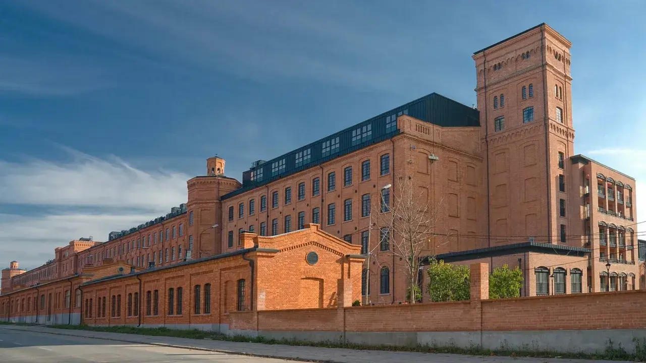 Dawny księży młyn, dziś nowoczesne centrum, lśni ceglaną fasadą pod błękitnym niebem.