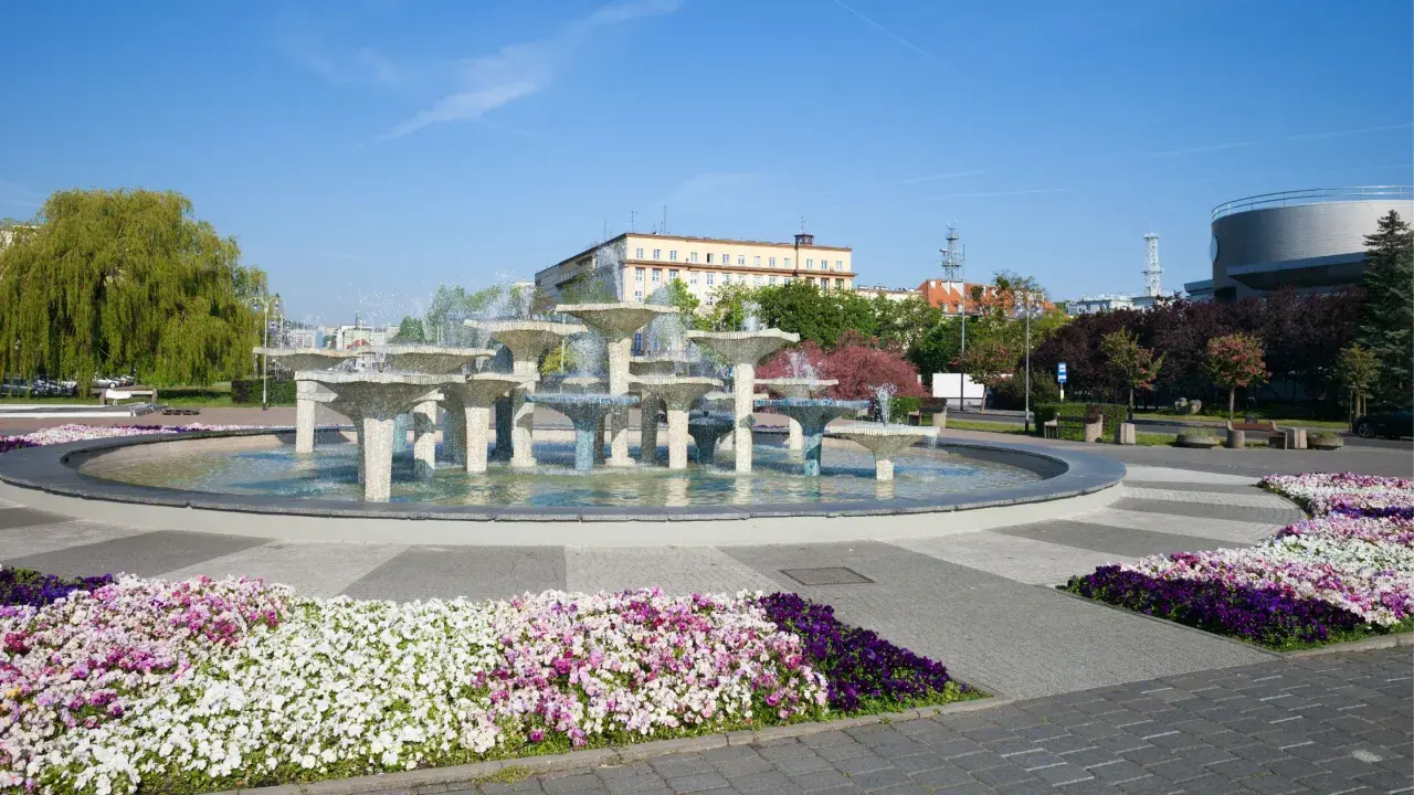 Fontanna w Gdyni stare miasto, otoczona kolorowymi kwiatami i zielenią, stanowi serce miejskiego placu.