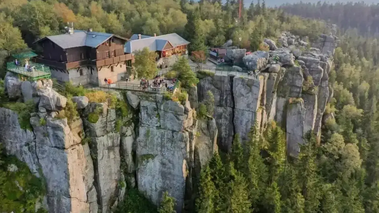 Schronisko na skalnej półce w Sudetach, Polska. Ludzie odpoczywają na tarasach z widokiem na las.