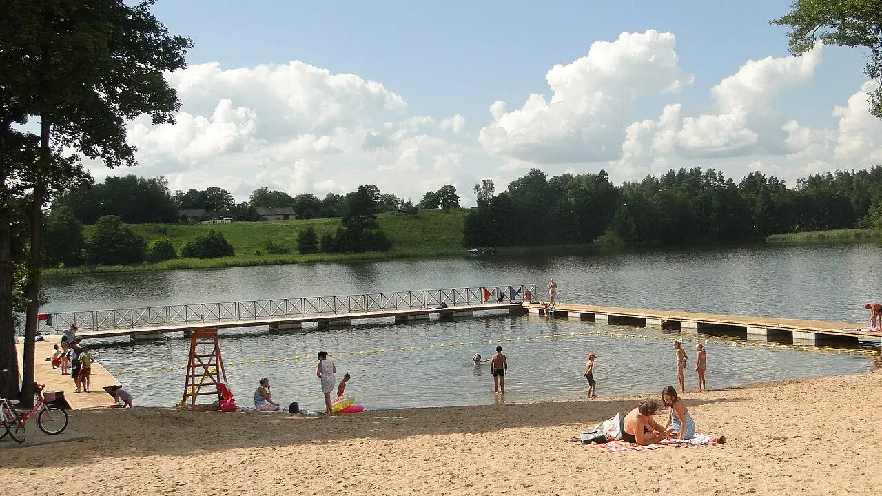 Słoneczne plaże na Mazurach. Ludzie odpoczywają na piasku i w wodzie, ciesząc się letnim dniem.