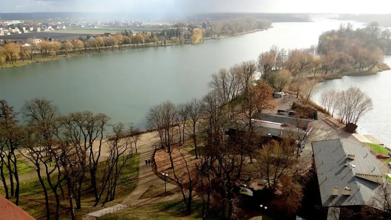 Malownicze jeziora w Kujawsko-Pomorskim, z drzewami w jesiennych barwach i miastem w tle.