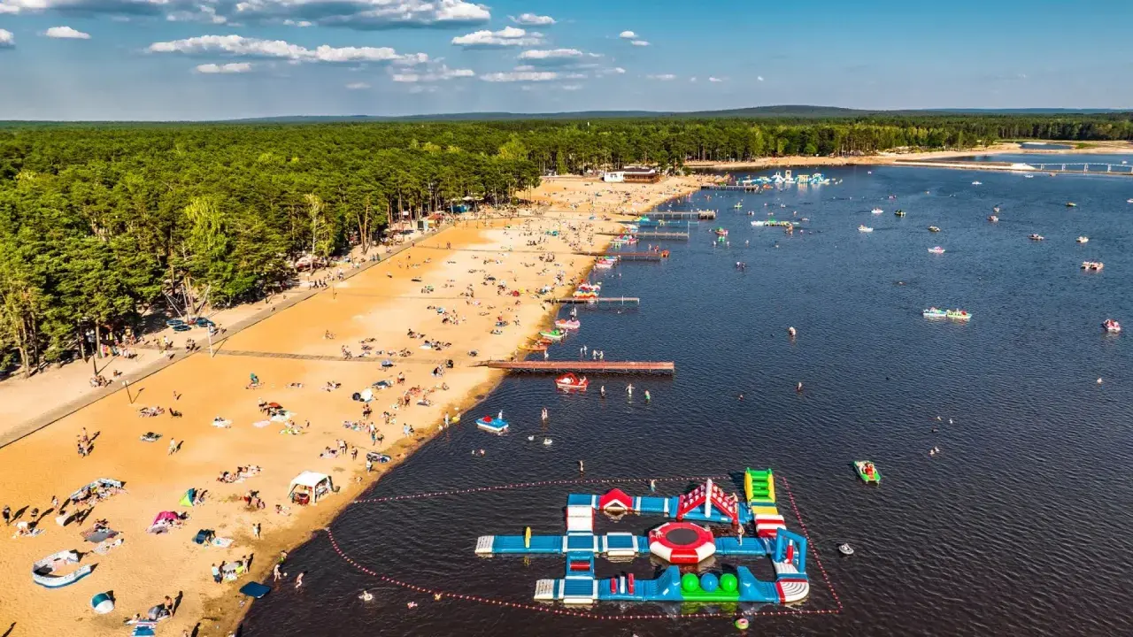 Słoneczny dzień na zalewach świętokrzyskich. Tłumy plażowiczów, wodne atrakcje i mnóstwo łódek na tafli wody.
