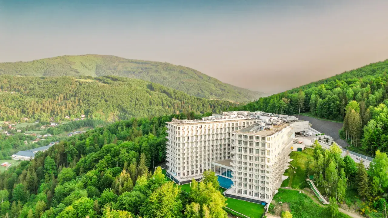 Nowoczesny hotel wtopiony w zieleń gór, przypominający kształtem górę czaszki.