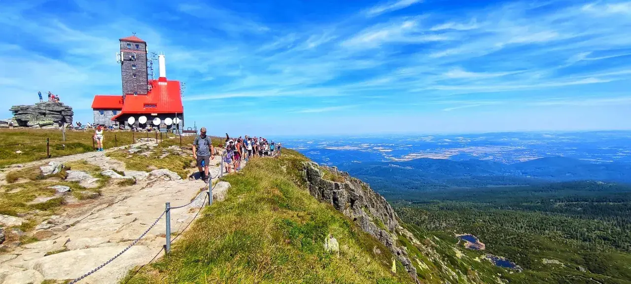 Grupa turystów wędruje ścieżką na Łabski Szczyt, podziwiając rozległą panoramę gór i dolin.