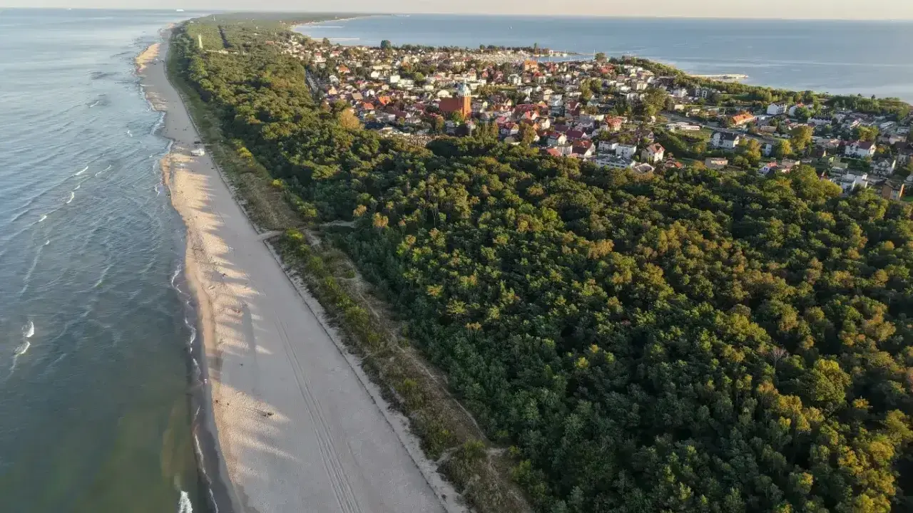 Piękna plaża i las, idealne miejsce, gdzie na majówkę. Widok z lotu ptaka na nadmorską miejscowość.