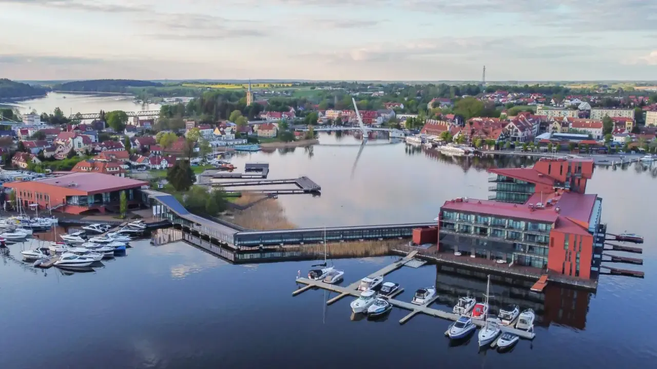 Mazury słyną z malowniczych jezior i portów pełnych jachtów. Widok na miasteczko z nowoczesnymi budynkami i wodnymi atrakcjami.