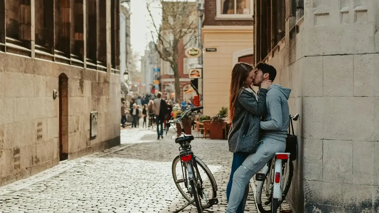 Zakochana para całuje się na brukowanej uliczce, obok rowerów. Idealne toruń atrakcje dla par na romantyczny spacer.