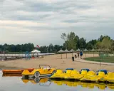Plaża z żółtymi rowerami wodnymi i łódkami, idealna na weekendowy wypad na Mazury blisko Warszawy.