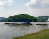 Jezioro Rożnowskie, gdzie jest? Widać tu łodzie przy pomoście, żaglówki na wodzie i zielone wzgórza.