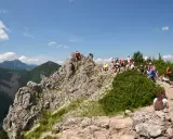 Grupa turystów odpoczywa na skalistym szczycie, podziwiając widok na **Dolinę Białego**.