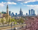 Majówka w Warszawie: zabytkowy kościół i nowoczesne wieżowce na tle kwitnącej wiśni.
