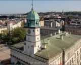 Widok na rynek na Kazimierzu w Krakowie z wieżą ratuszową i zielonymi dachami.