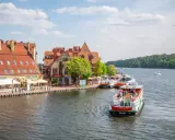 Port w Giżycku, gdzie cumują statki wycieczkowe, to jedna z głównych atrakcji miasta. W tle malownicze kamieniczki i zielone lasy.