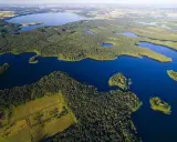 Malownicze jeziora na Mazurach otoczone gęstymi lasami, z widokiem na pola i dalsze akweny.