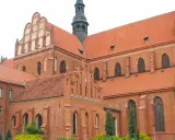 Majestatyczna pelplińska katedra z cegły, z charakterystycznymi dachami i wieżą, góruje nad otoczeniem.