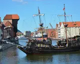 Gdański galeon "Lew" z pasażerami na pokładzie, na tle zabytkowej architektury miasta. To jeden z 7 ciekawych faktów o Polsce, które można odkryć w tym mieście.