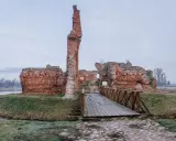 Ruiny zamku w okolicach Łodzi tak do 100 km. Drewniany mostek prowadzi do ceglanych murów.