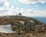 Szklarska Poręba jakie góry? Widok na Karkonosze z budynkiem na szczycie, skaliste zbocza i resztki śniegu.