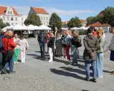 Grupa turystów słucha przewodnika na rynku w Chełmnie, poznając lokalną trasę.