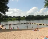 Słoneczne plaże na Mazurach. Ludzie odpoczywają na piasku i w wodzie, ciesząc się letnim dniem.