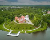 Zamek w Gostyninie, perła pojezierza gostynińsko-włocławskiego, wznosi się nad jeziorem, otoczony zielenią.