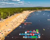 Słoneczny dzień na zalewach świętokrzyskich. Tłumy plażowiczów, wodne atrakcje i mnóstwo łódek na tafli wody.