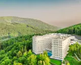 Nowoczesny hotel wtopiony w zieleń gór, przypominający kształtem górę czaszki.