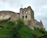 Zamek Czorsztyn, majestatyczna ruina na wzgórzu, z polską flagą powiewającą na wieży.