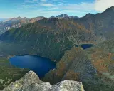 Widok na Tatry z góry. Na pierwszym planie skały, w dole las i jezioro Morskie Oko.