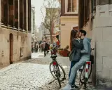 Zakochana para całuje się na brukowanej uliczce, obok rowerów. Idealne toruń atrakcje dla par na romantyczny spacer.