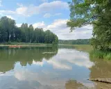 Spokojne jezioro w Mazurskim Parku Krajobrazowym. Dwie kajaki płyną po wodzie, otoczone zielenią lasów i trzcin. To idealne miejsce na relaks i podziwianie przyrody.