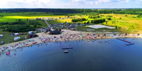 Tłumy ludzi wypoczywają na plaży i w wodzie. Idealne miejsce, gdzie nad wodę Dolny Śląsk zaprasza na wakacje.