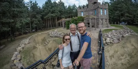 Rodzina pozuje do zdjęcia na tle kamiennego zamku, jednego z romantycznych miejsc na Podlasiu.