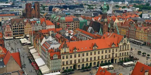Widok z góry na kolorowy rynek z kamienicami, ratuszem i kościołem. To chyba najładniejszy rynek w Polsce, tętniący życiem.