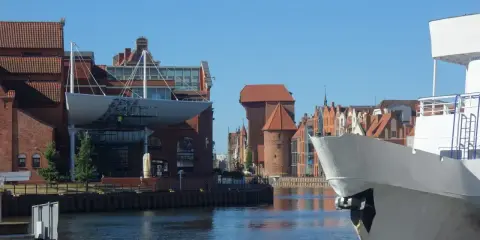 Gdańsk Starówka atrakcje: biały statek na pierwszym planie, w tle zabytkowe kamienice i Żuraw.