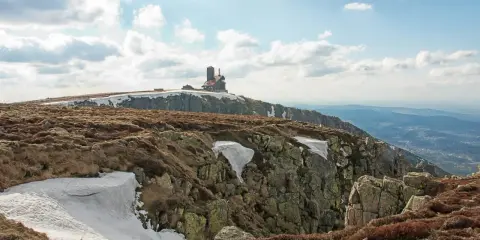 Szklarska Poręba jakie góry? Widok na Karkonosze z budynkiem na szczycie, skaliste zbocza i resztki śniegu.