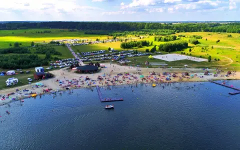 Tłumy ludzi wypoczywają na plaży i w wodzie. Idealne miejsce, gdzie nad wodę Dolny Śląsk zaprasza na wakacje.