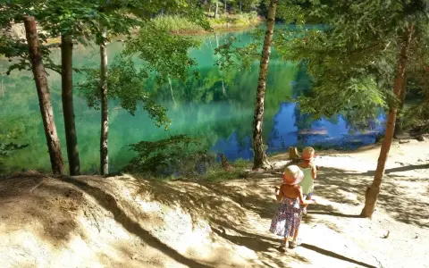 Dwie dziewczynki w słomkowych kapeluszach idą ścieżką w stronę turkusowego jeziora.