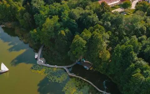 Idealne miejsce, gdzie nad jezioro w Polsce. Drewniana kładka prowadzi do łodzi i żaglówki, otoczone bujną zielenią.