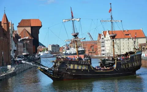 Gdański galeon "Lew" z pasażerami na pokładzie, na tle zabytkowej architektury miasta. To jeden z 7 ciekawych faktów o Polsce, które można odkryć w tym mieście.