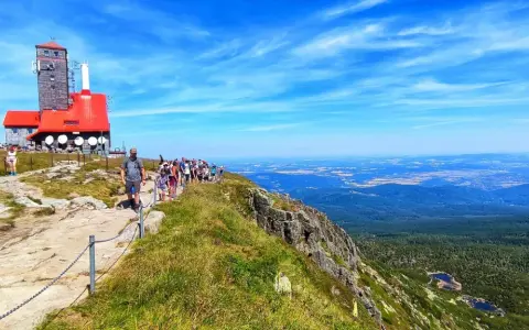 Grupa turystów wędruje ścieżką na Łabski Szczyt, podziwiając rozległą panoramę gór i dolin.